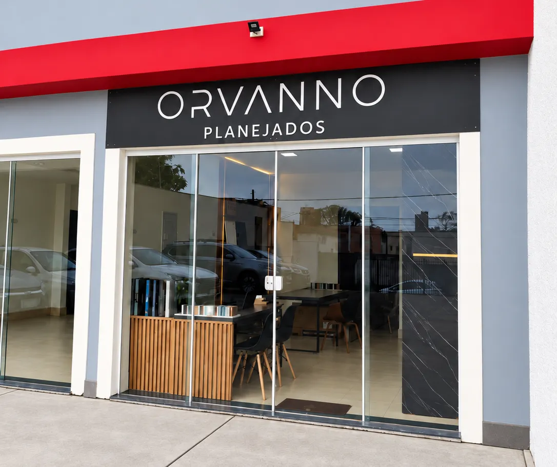 Fachada da loja e showroom Orvanno Planejados, com a faixa vermelha, o letreiro sobre a porta de vidro e o atendimento à vista.