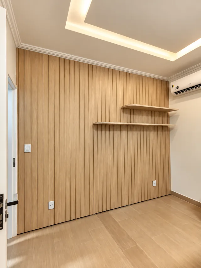 Parede com painel ripado de madeira clara, prateleiras e forro de gesso com iluminação embutida.