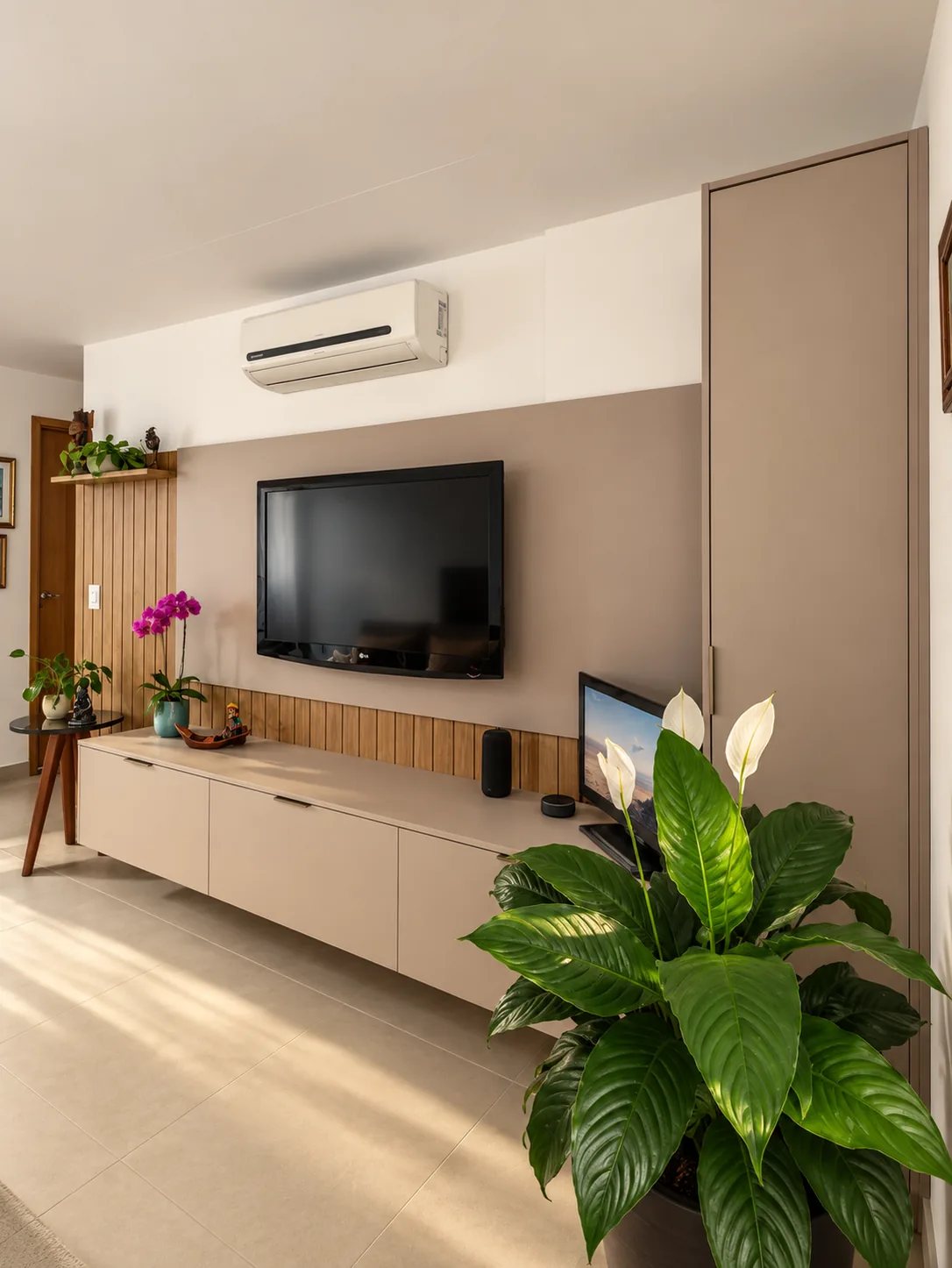 Sala com rack suspenso, painel da televisão e armário alto na cor bege.